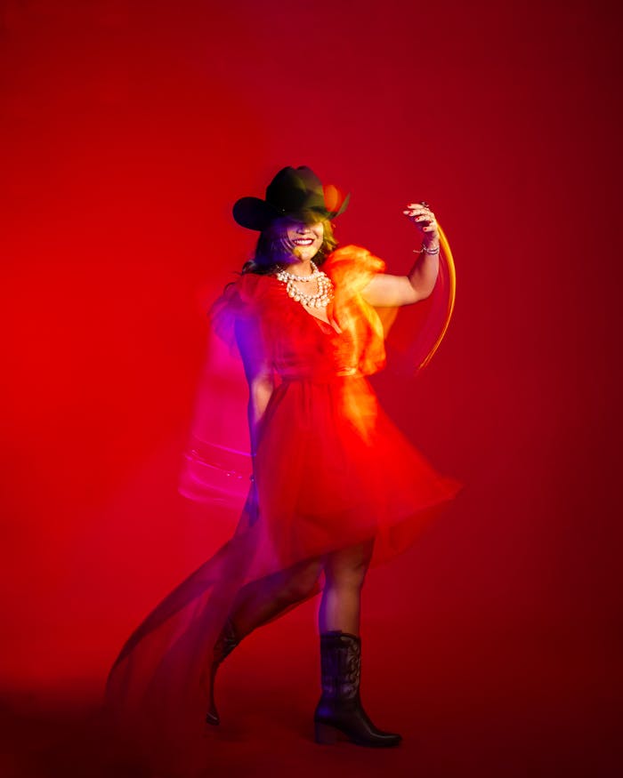 Dynamic image of a cowgirl dancer in a red dress showcasing movement and fashion.