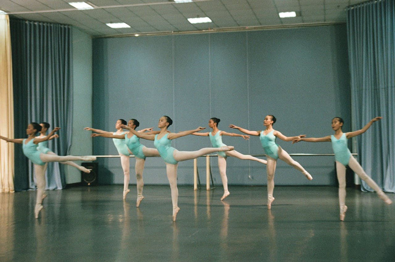 Group of young dancers practicing ballet in a studio setting with focus on grace and technique.