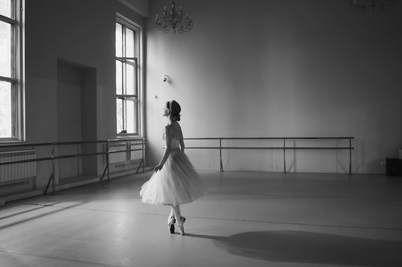 Graceful ballerina captured in a monochrome ballet studio setting, exuding elegance and discipline.