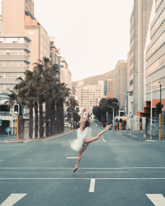 Ballet dancer elegantly poses in a city street, showcasing grace and movement against an urban backdrop.